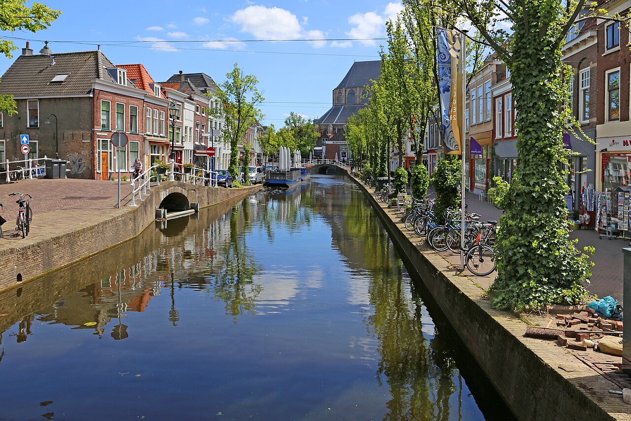Canal bordeado de árboles y casas de ladrillo en el centro de Delft