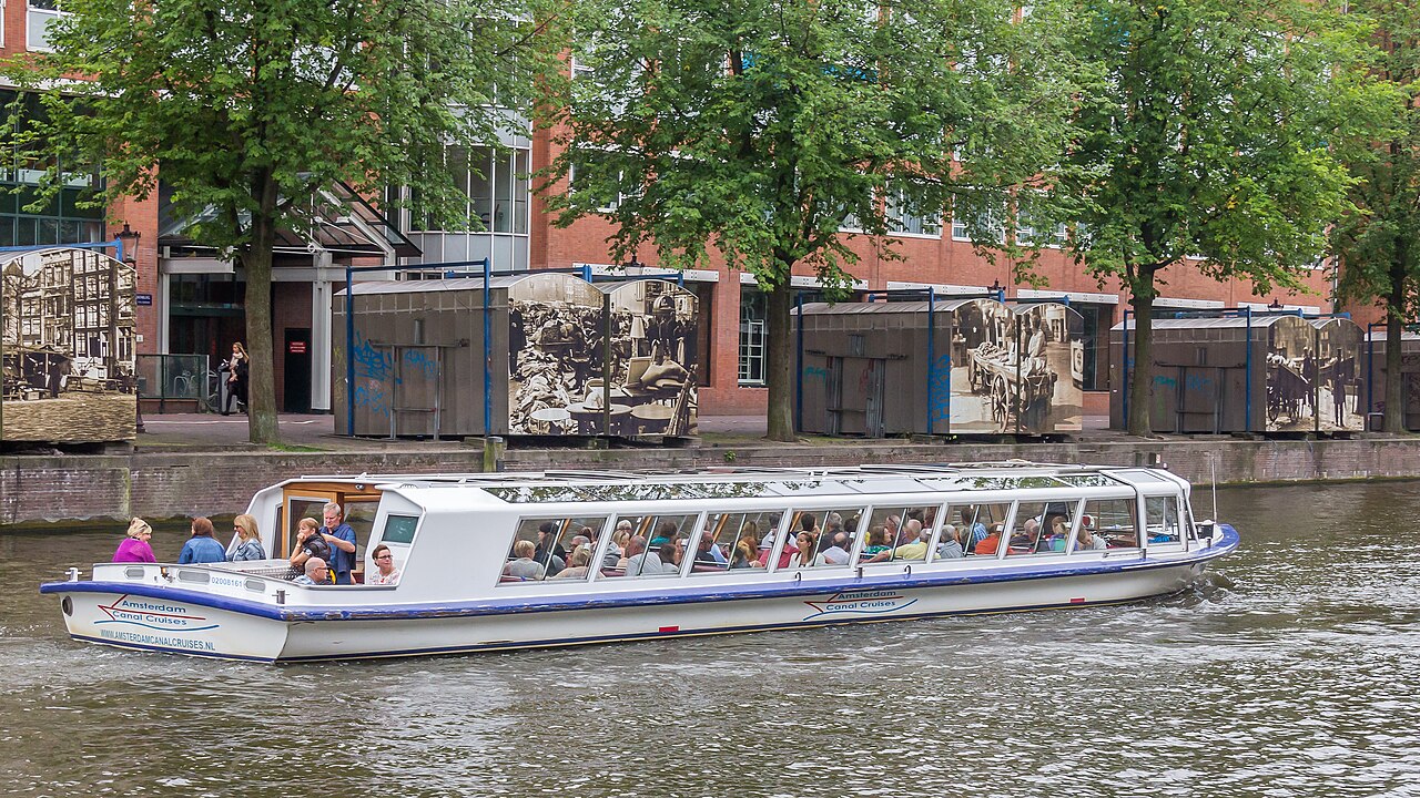 Bateau de croisière à toit vitré sur un canal d'Amsterdam