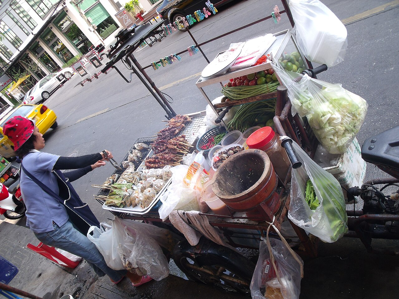 Vendeuse de brochettes grillées sur un étal de rue à Bangkok