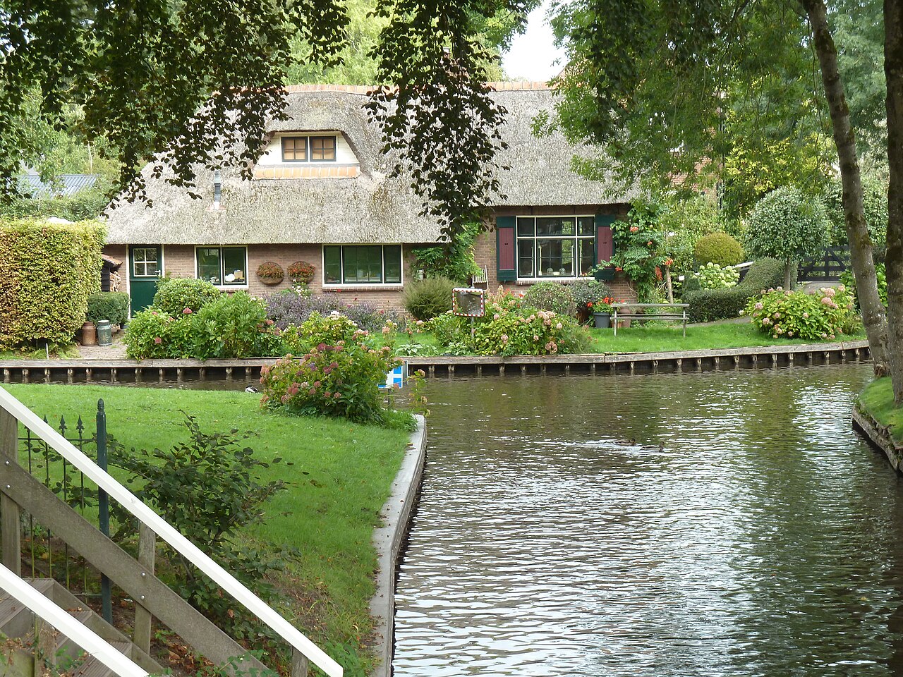 Una granja con techo de paja y su jardín a orillas de un canal de Giethoorn