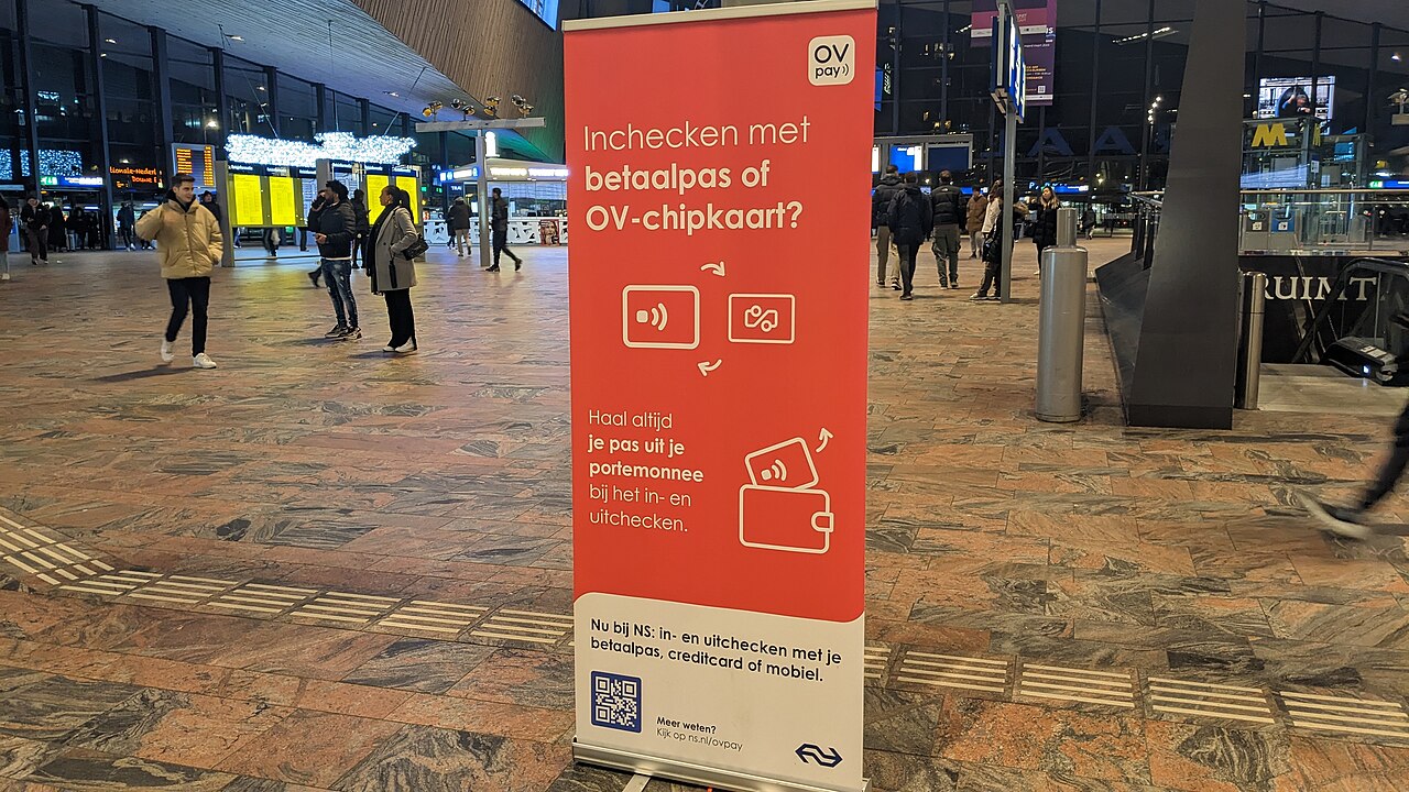 Cartel de OVpay que invita a validar con tarjeta bancaria u OV-chipkaart, en una estación neerlandesa