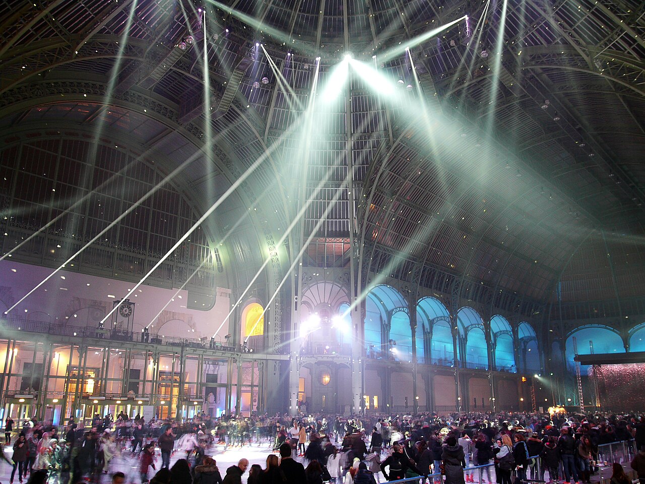 La nef du Grand Palais transformée en patinoire, balayée par des faisceaux lumineux