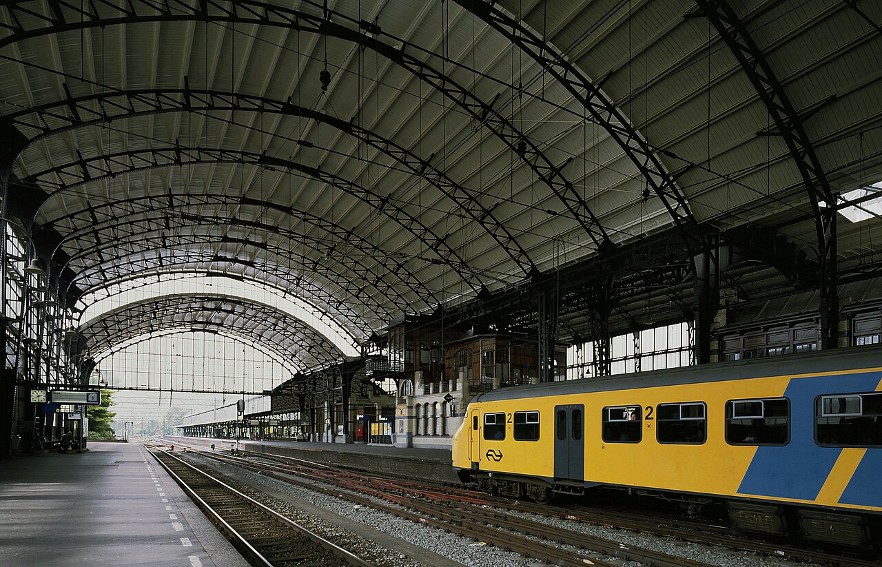 The large glass roof over the platforms of Haarlem station, with an NS train