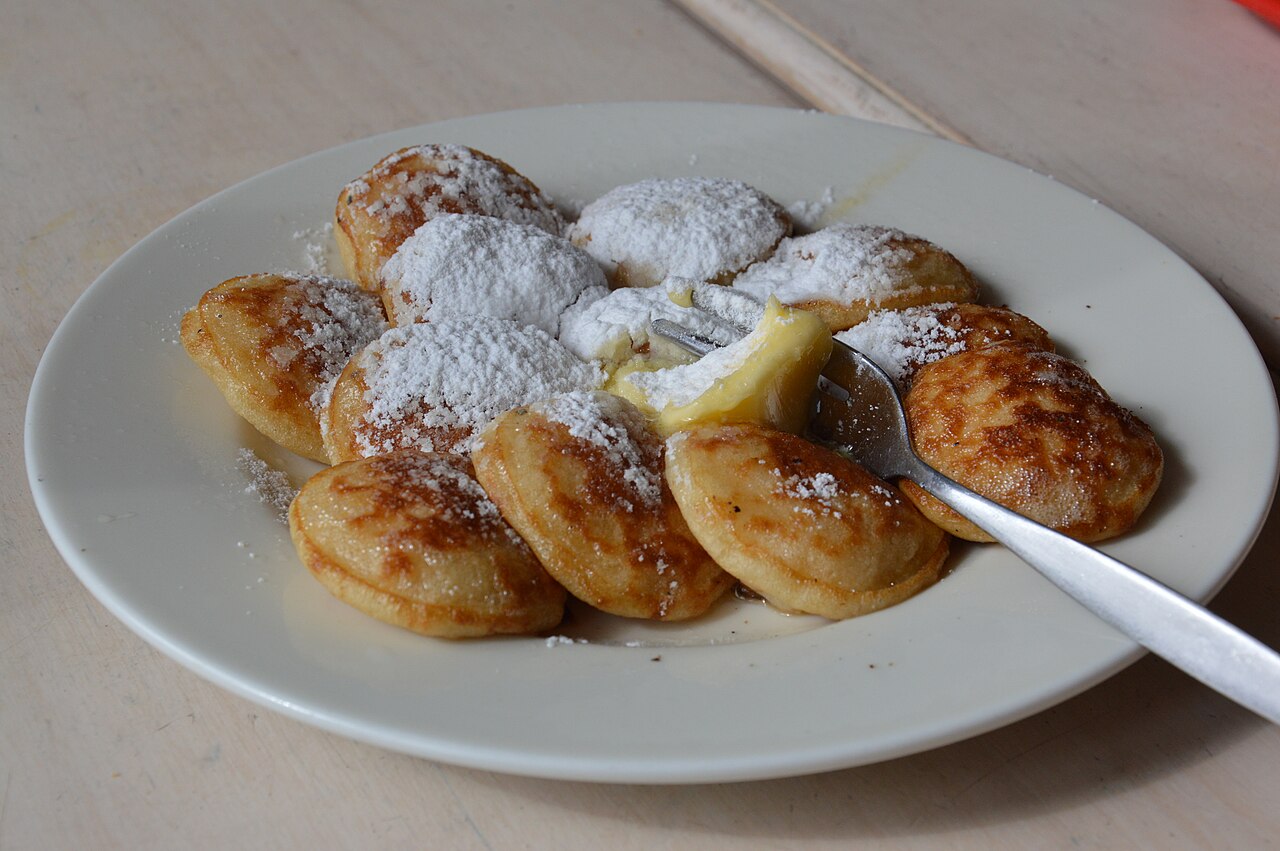 Een bord poffertjes met boter en poedersuiker