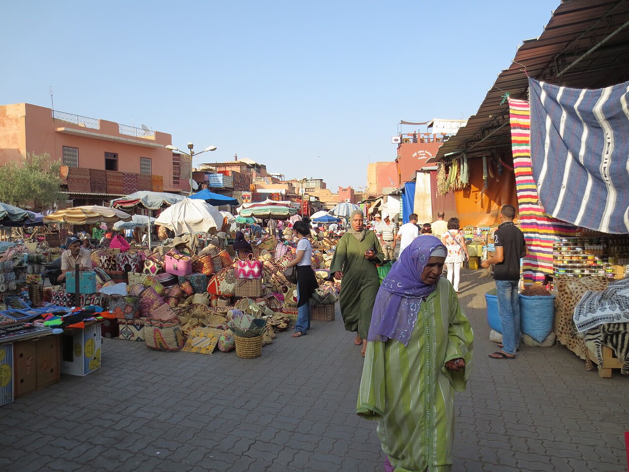 Passants en djellaba dans une rue commerçante de la médina de Marrakech