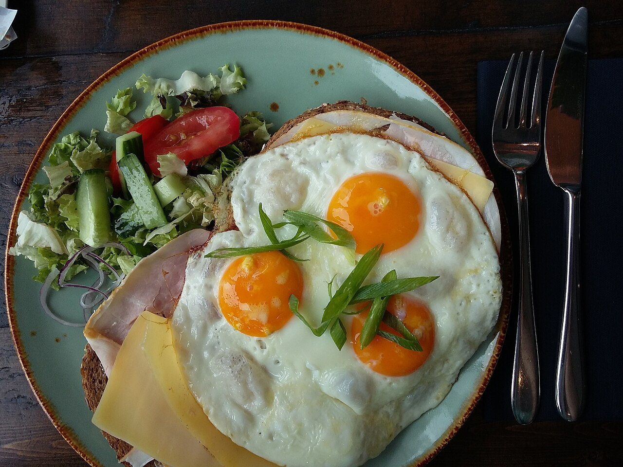 Een uitsmijter ham-kaas: gebakken eieren op brood, met salade
