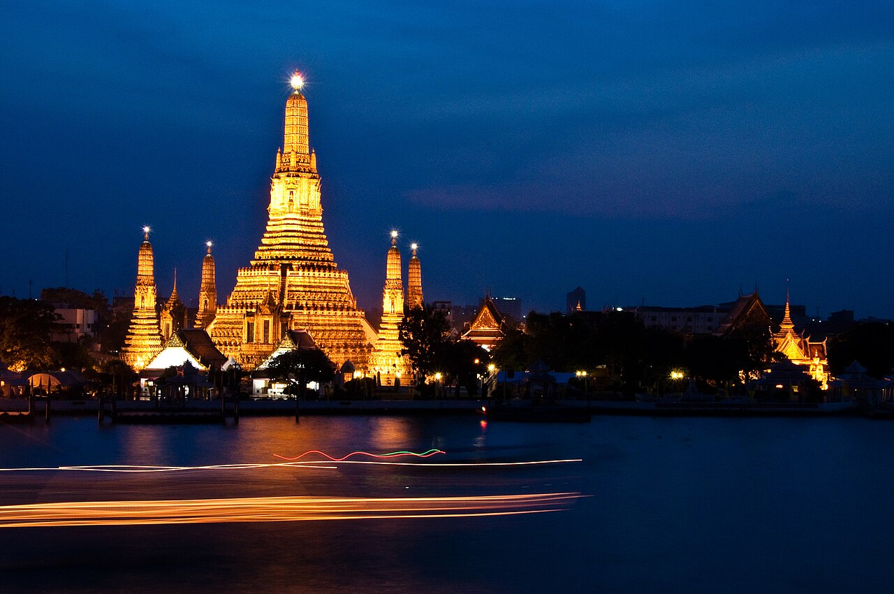 Wat Arun illuminé, avec les traînées lumineuses d'un bateau de croisière sur le Chao Phraya